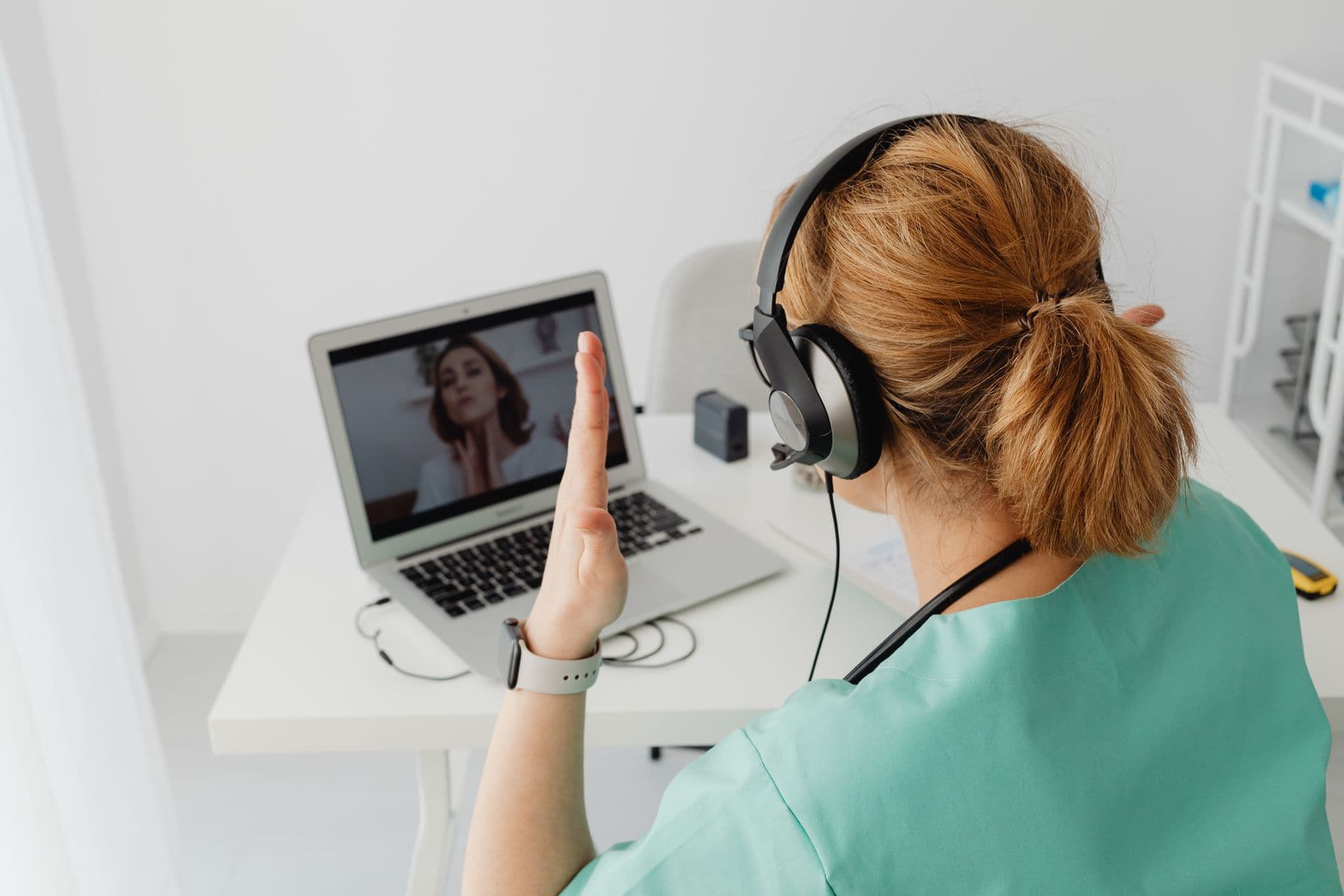 Médica atendendo por vídeo, com o paciente na tela
